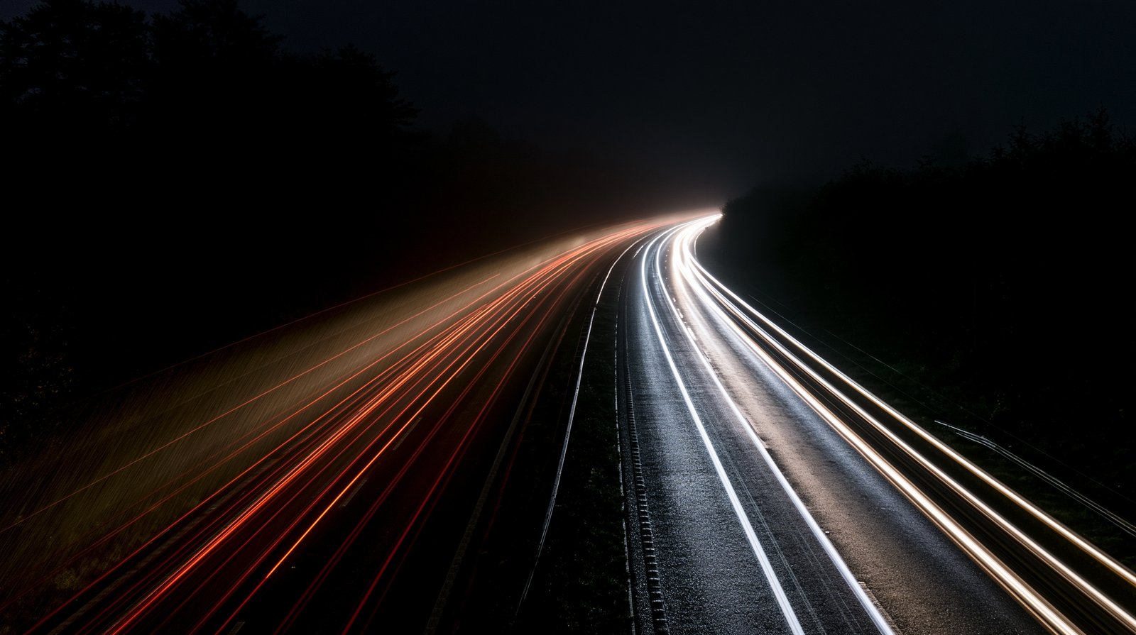 Night motorway with long-exposure headlight trails.